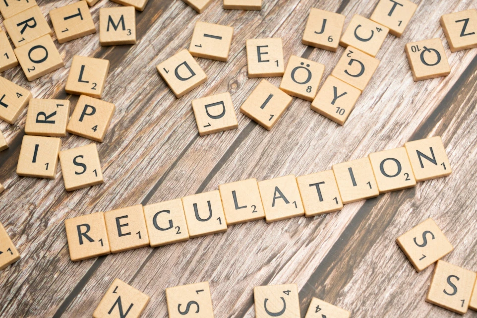 scrabble tiles spelling out the word regulation on a wooden surface